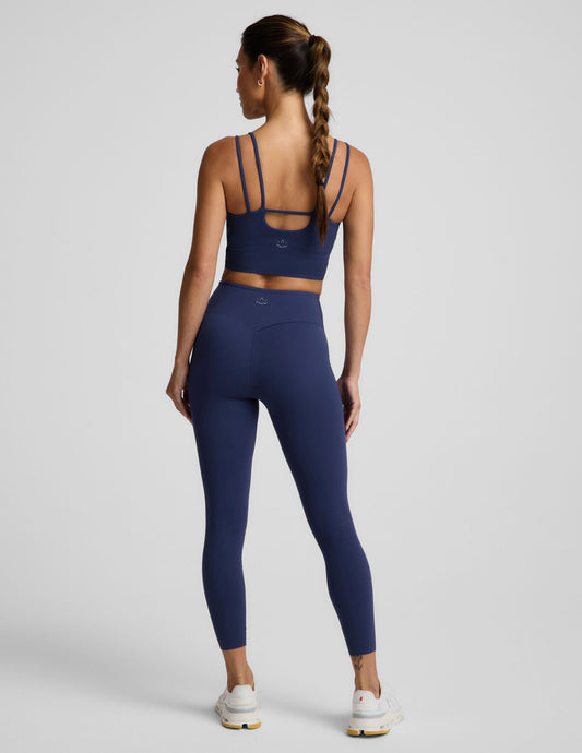 Woman wearing a blue cropped tank and blue midi leggings against a plain background.