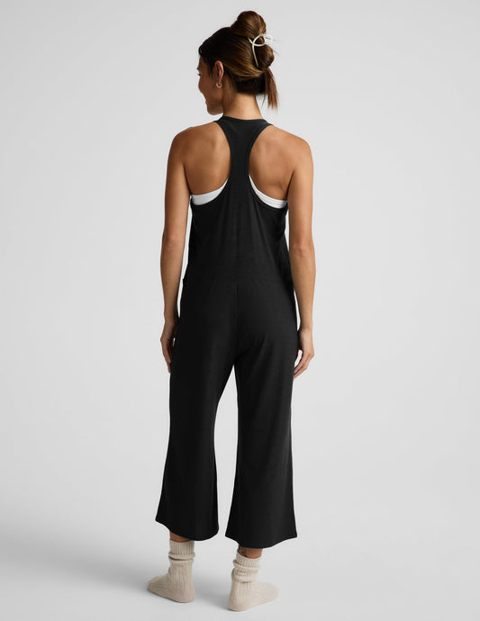 Woman wearing a black tank jumpsuit against a plain background.