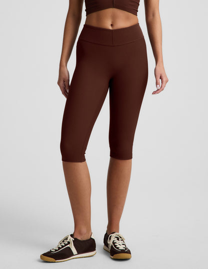 Woman wearing Brown Impulse Ribbed V-Waist Pedal Pusher Legging™ with a matching ribbed crop top and brown sneakers.