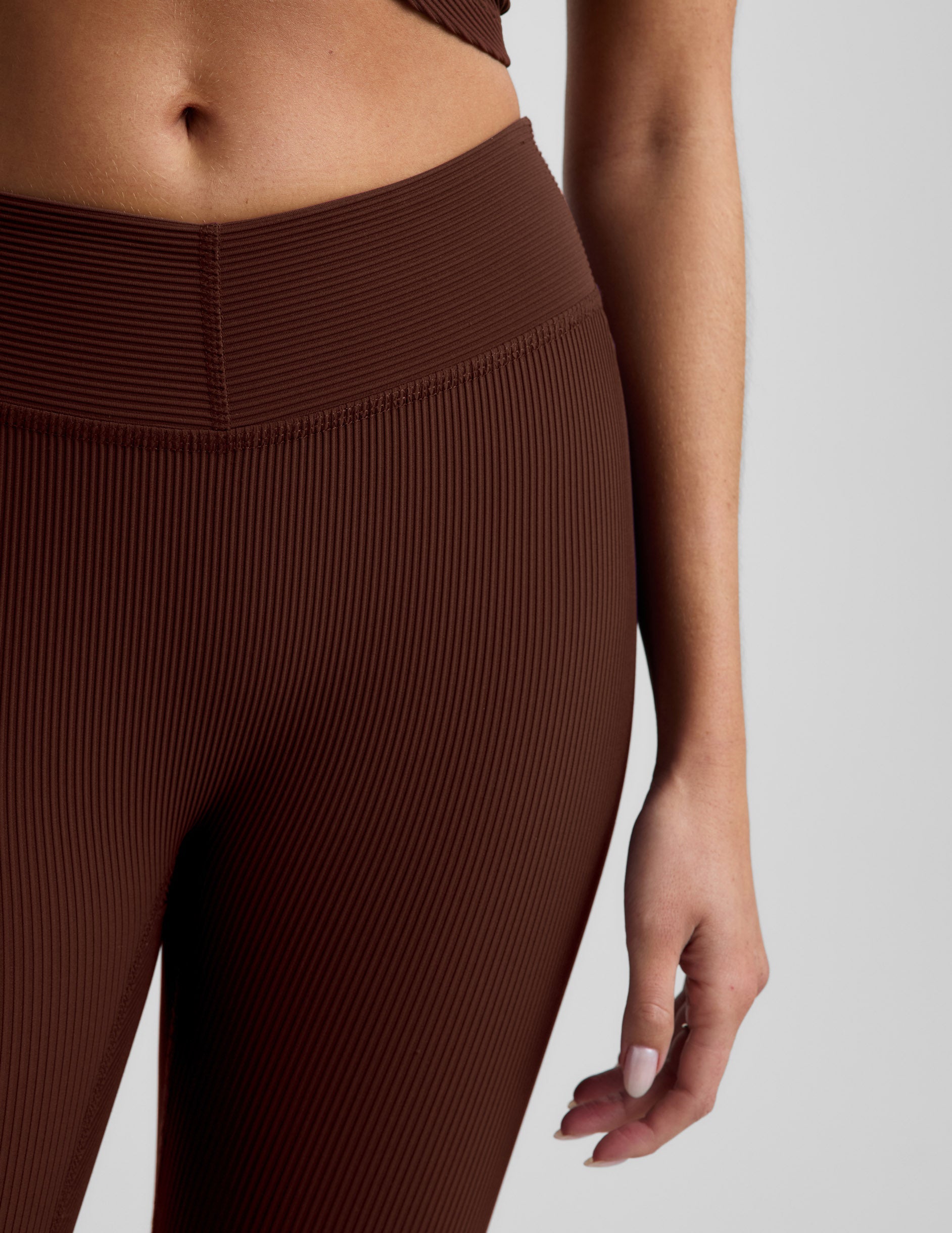 Woman wearing Brown Impulse Ribbed V-Waist Pedal Pusher Legging paired with a matching top, showing the ribbed V-waistband.