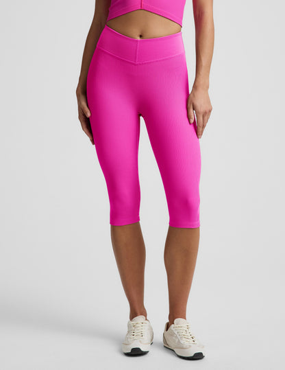 Woman wearing Pink Impulse Ribbed V-Waist Pedal Pusher Legging paired with a matching top and cream sneakers.