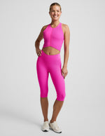 Woman wearing Pink Impulse Ribbed V-Waist Pedal Pusher Legging paired with a matching pink tank top and cream sneakers.