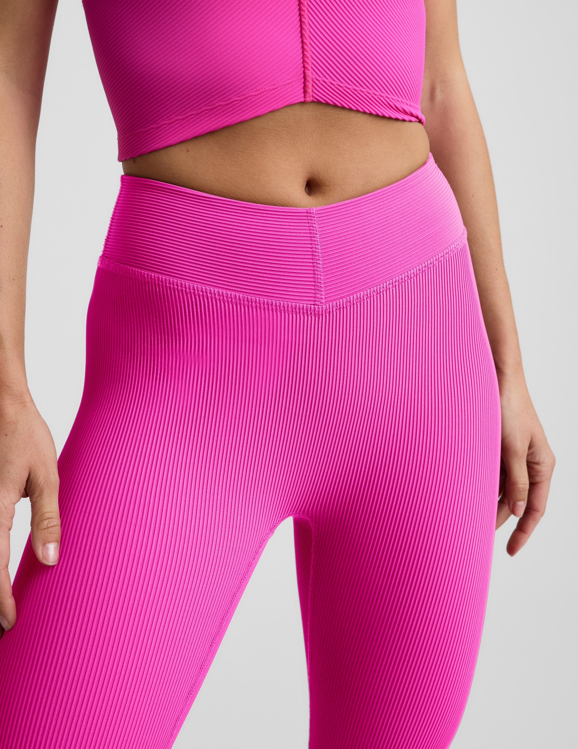 Woman wearing Pink Impulse Ribbed V-Waist Pedal Pusher Legging™ paired with a matching pink ribbed top.