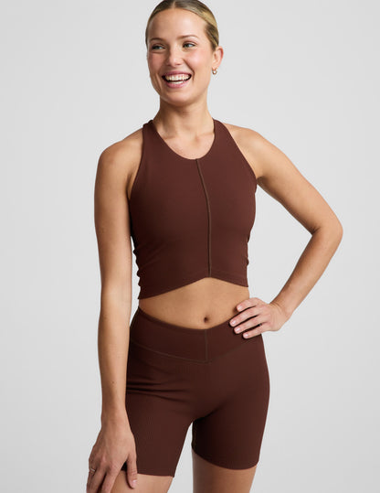Woman wearing a brown ribbed cropped tank and brown ribbed shorts against a plain background.