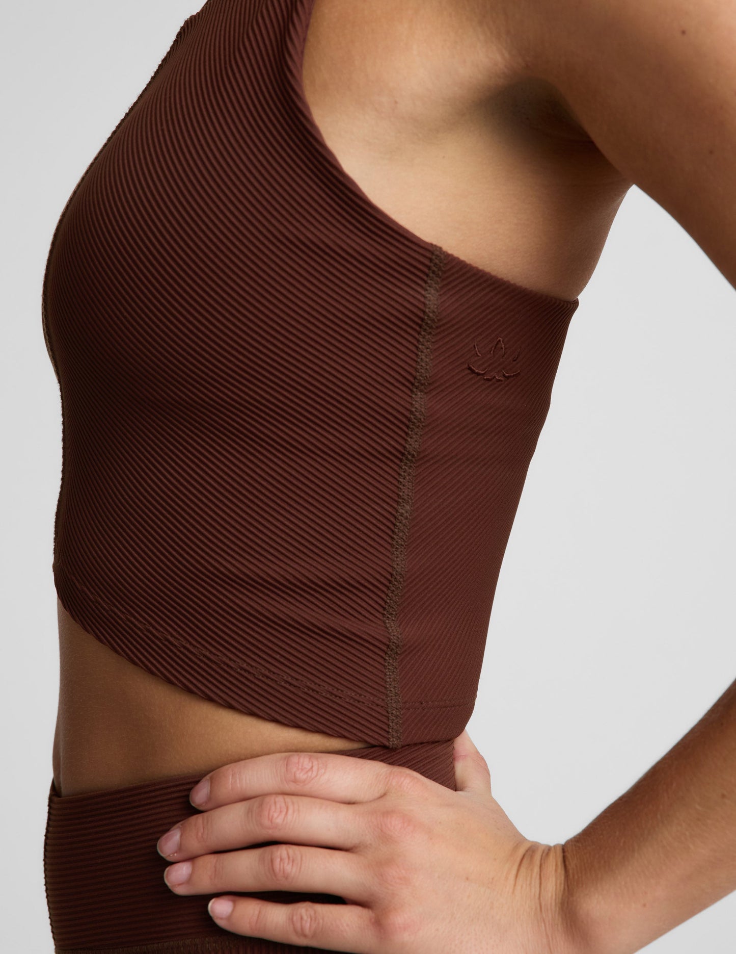Woman wearing a brown ribbed cropped tank and brown ribbed shorts against a plain background.