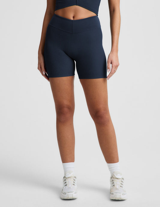 Woman wearing Navy Impulse™ Ribbed V-Waist 5" Biker Short paired with white sneakers.