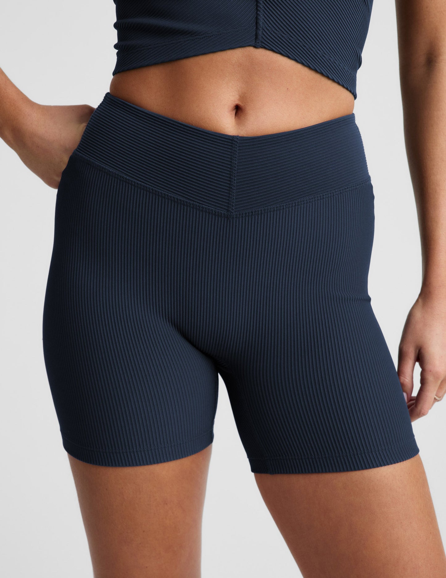 Woman wearing Navy Impulse Ribbed V-Waist 5" Biker Short™ with a v-waistband and ribbed texture, paired with a matching top.