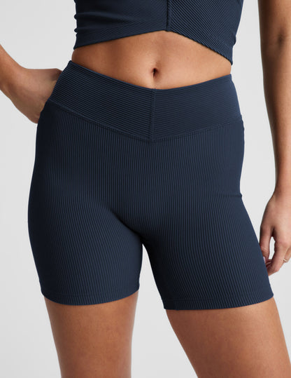 Woman wearing Navy Impulse Ribbed V-Waist 5" Biker Short™ with a v-waistband and ribbed texture, paired with a matching top.