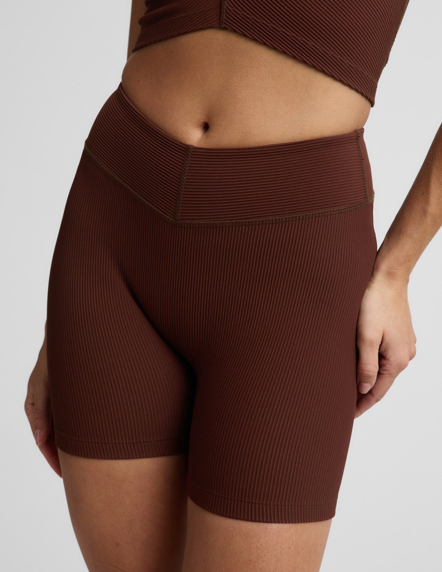 Woman wearing Brown Impulse Ribbed V-Waist 5" Biker Short™ with a ribbed V-waistband, paired with a matching top.