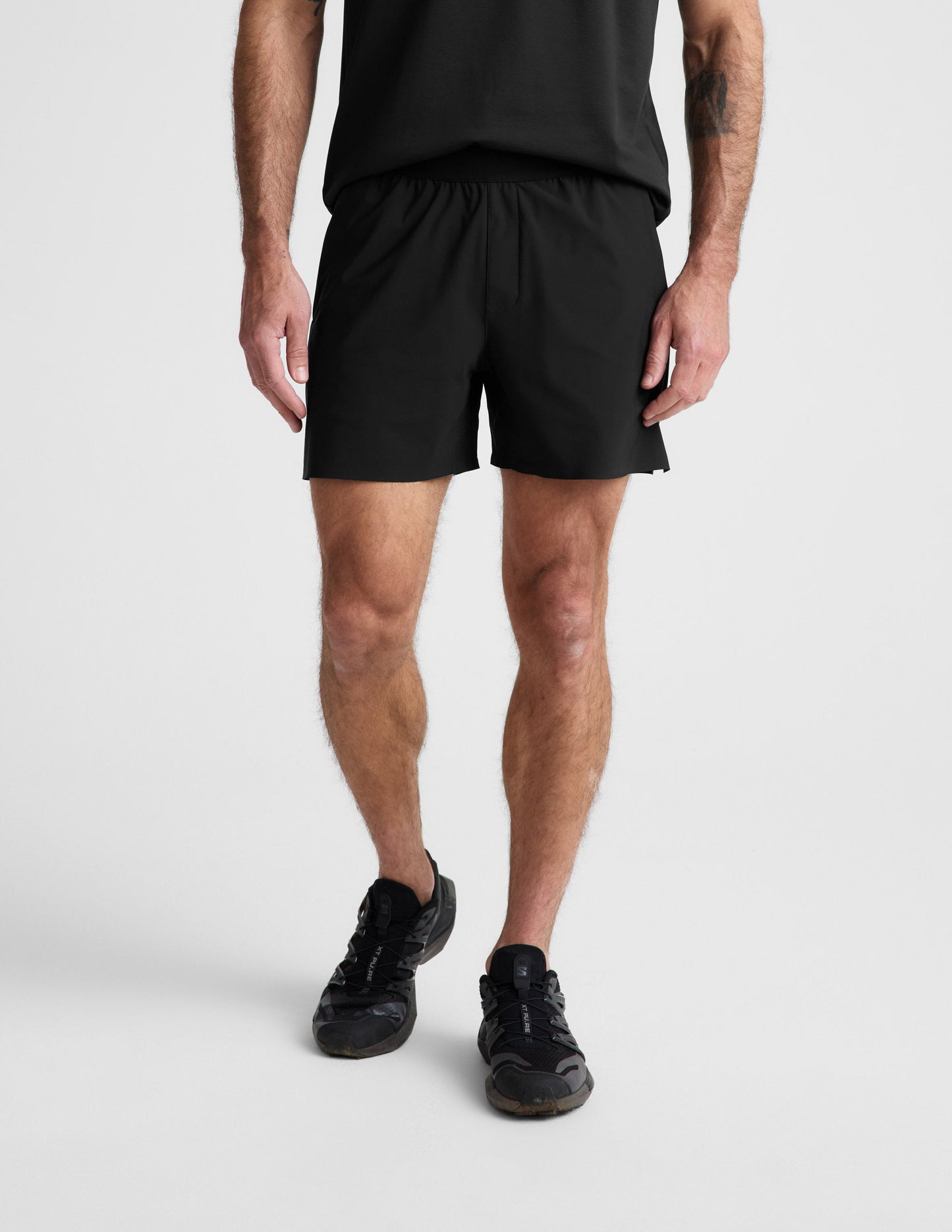 Man wearing black WarpLite™ Range Lined Short with an elastic waistband, paired with a black t-shirt and sneakers.