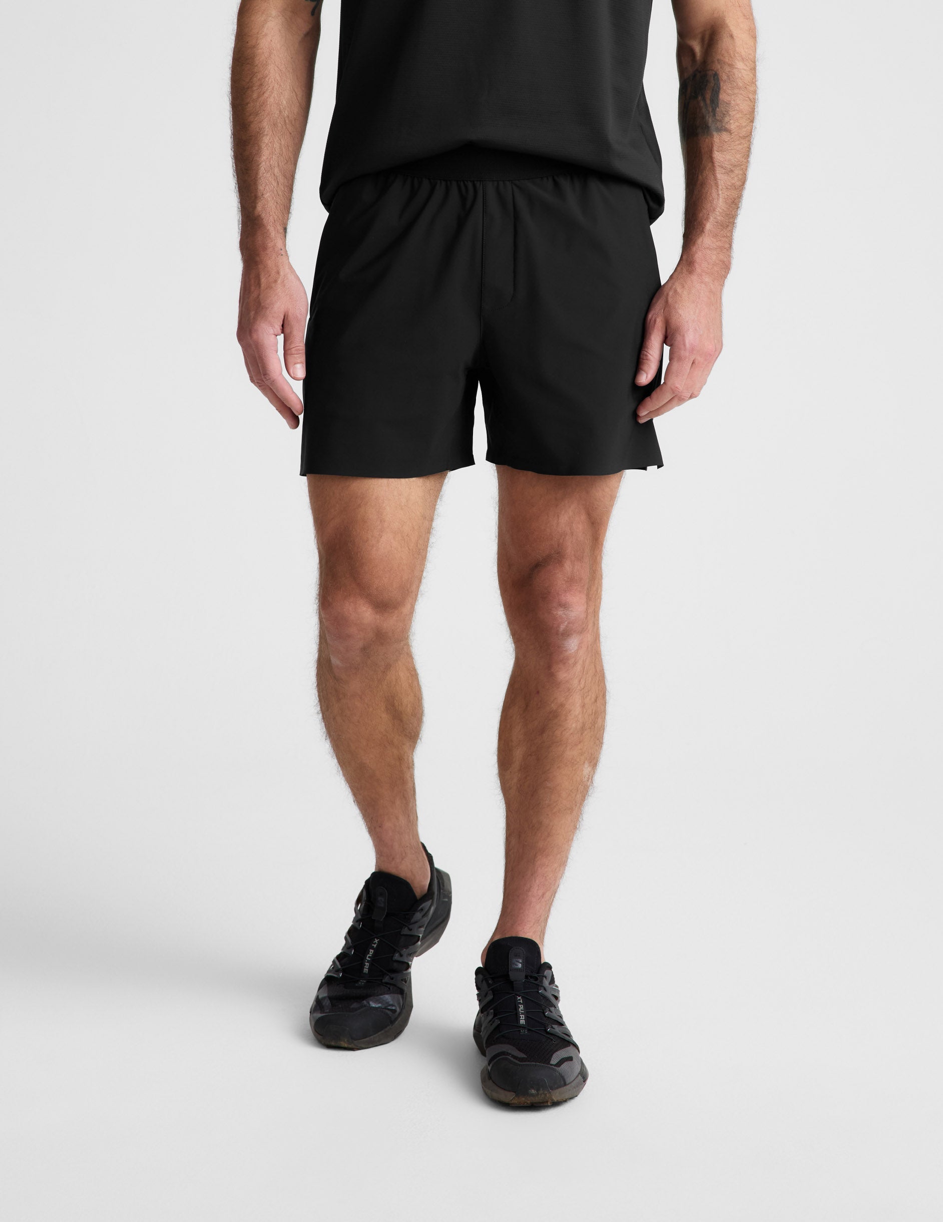 Man wearing black WarpLite™ Range Lined Short with an elastic waistband, paired with a black t-shirt and sneakers.