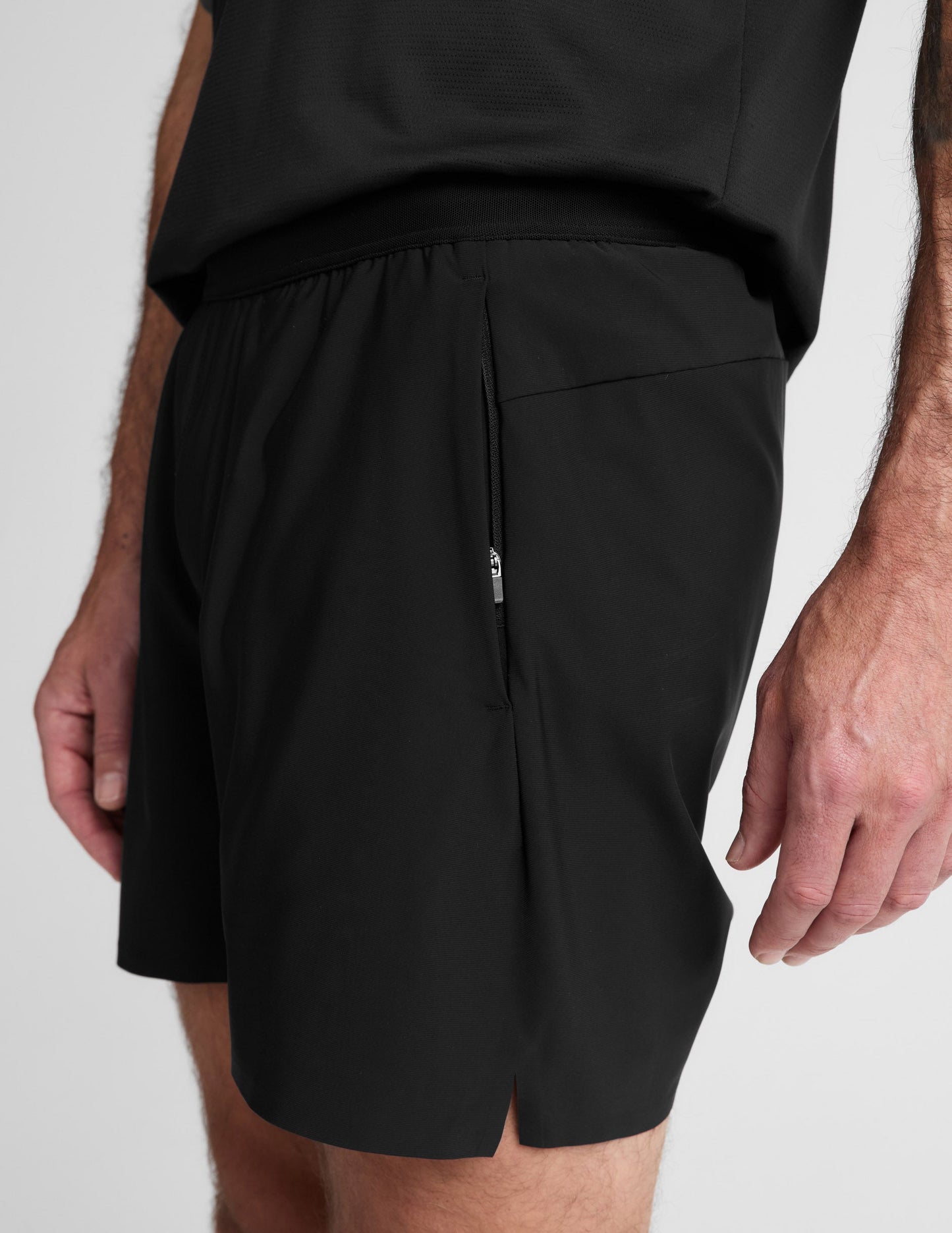 Man wearing Black WarpLite Range Lined Short™ with a black t-shirt, showing a side zipper pocket and elastic waistband.