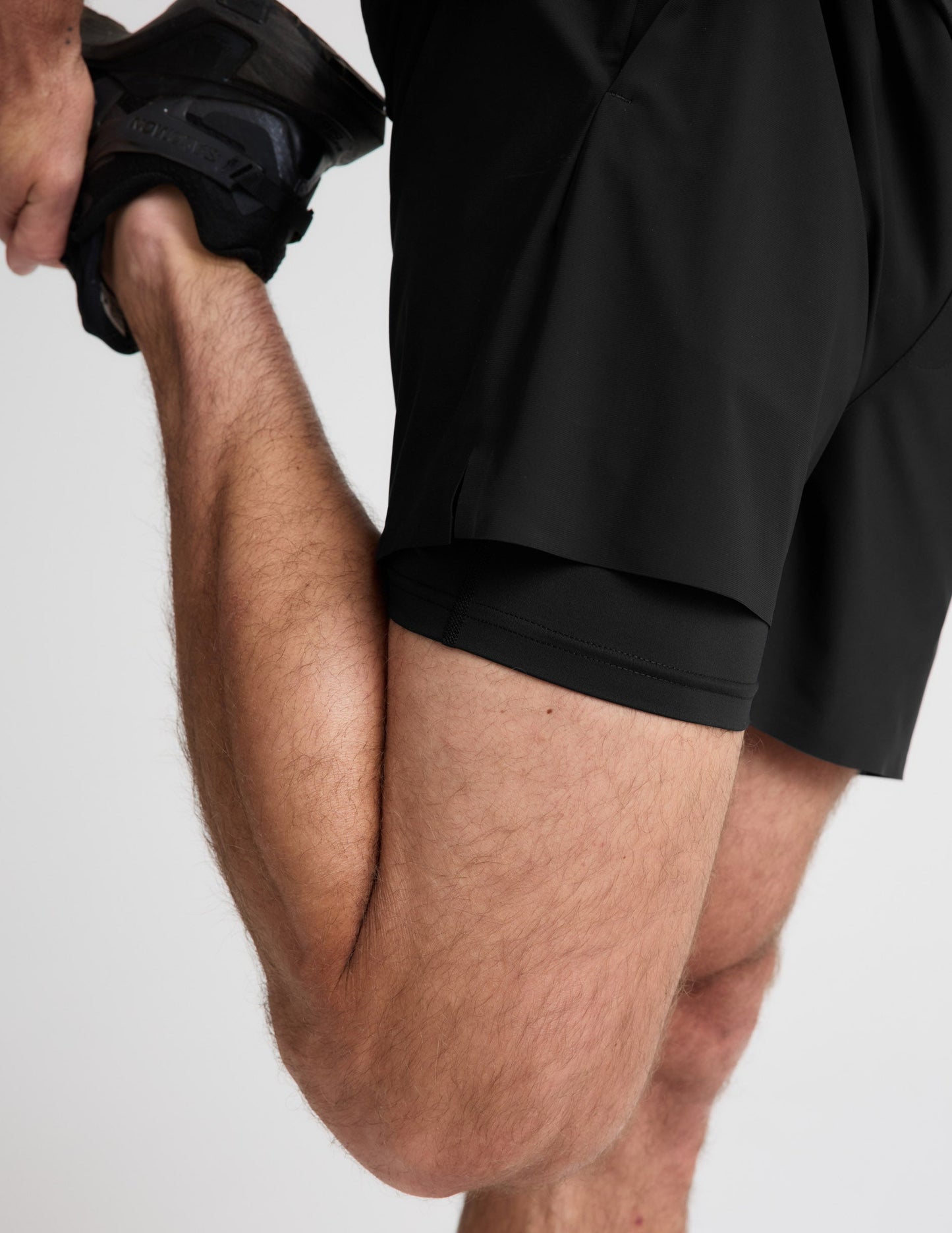 Close-up of man wearing Black WarpLite Range Lined Short™ paired with black sneakers, showing the inner liner detail.
