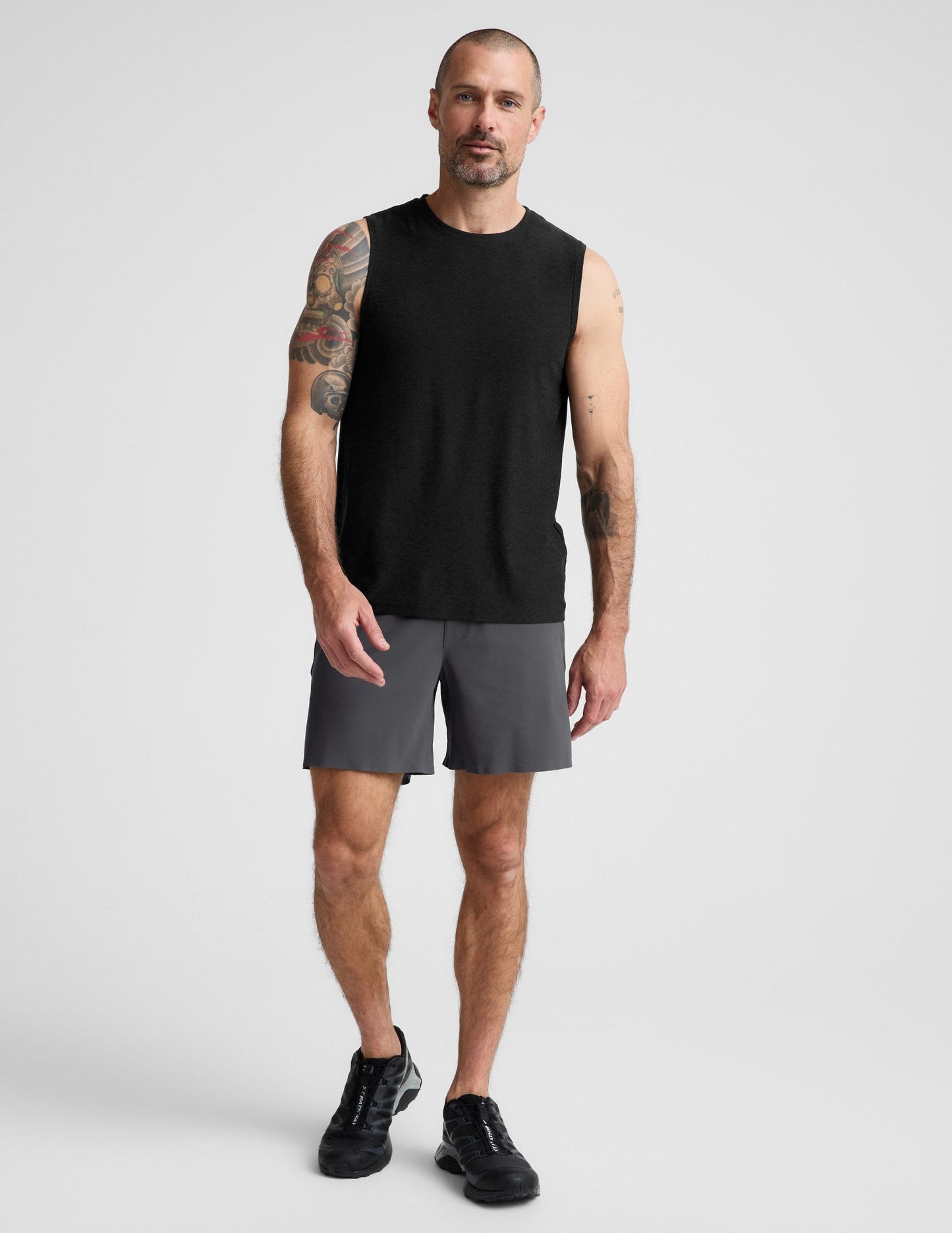 Man wearing Gray WarpLite™ Range Lined Short with a 6-inch inseam, paired with a black tank top and black sneakers.