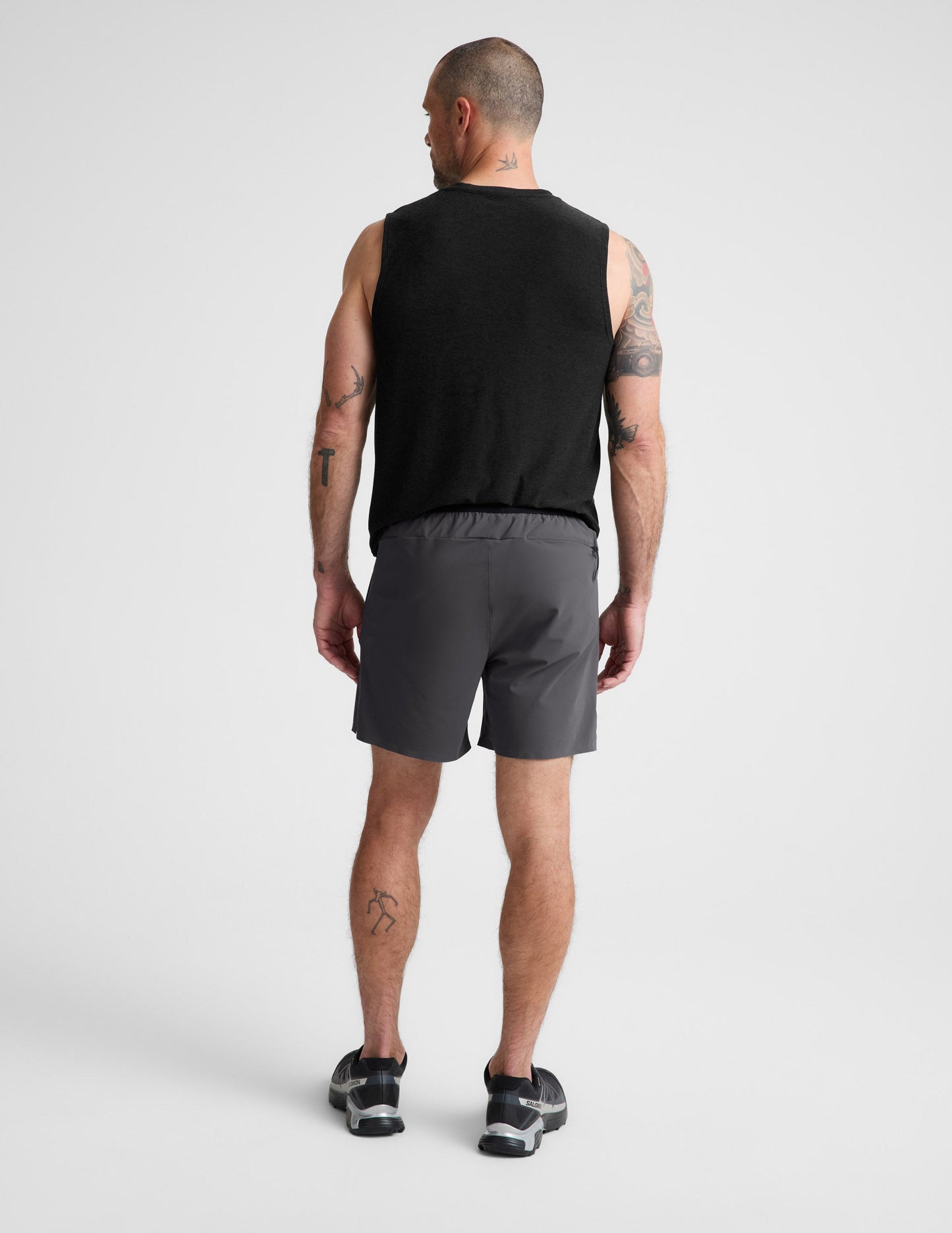 Man wearing Gray WarpLite Range Lined Short™ paired with a black tank top and sneakers, Rear view.
