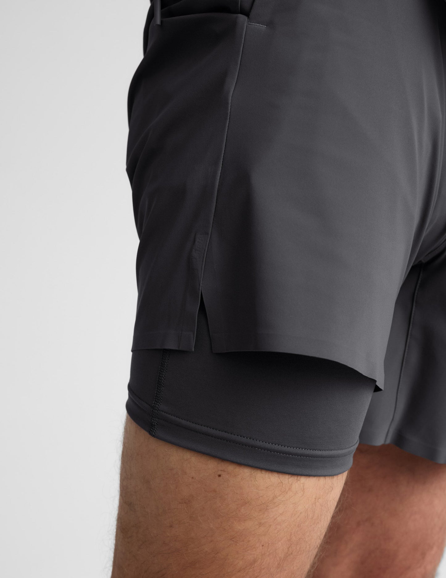 Side profile of man wearing Gray WarpLite Range Lined Short™ showing the side slit and exposed compression liner.