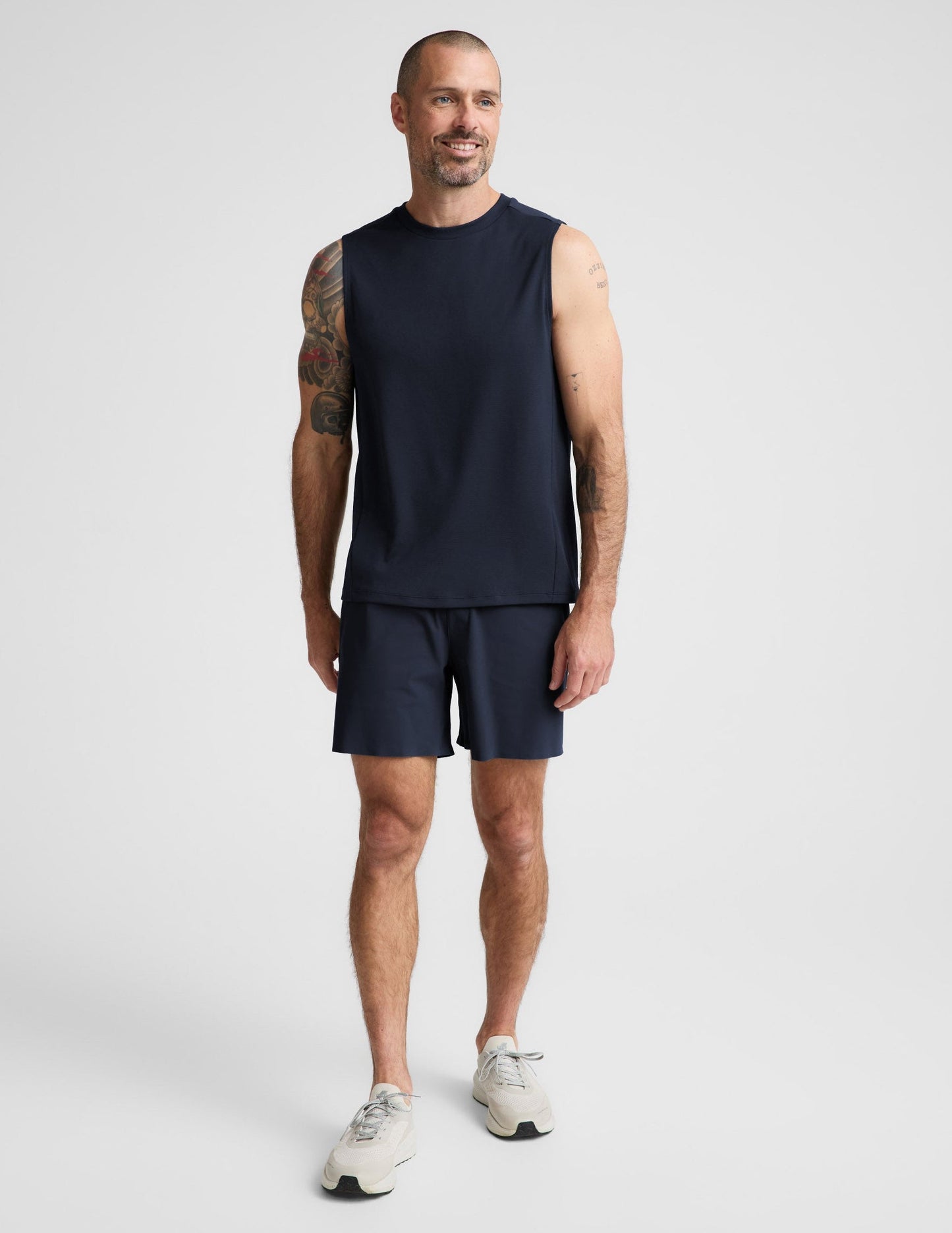 Man wearing Navy WarpLite Range Lined Short™ with a navy sleeveless shirt and cream sneakers.