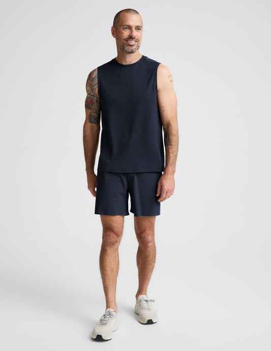 Man wearing Navy WarpLite Range Lined Short™ with a navy sleeveless shirt and cream sneakers.