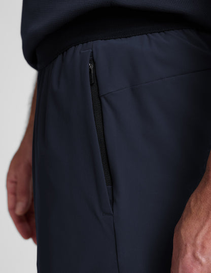 Man wearing Navy WarpLite Range Lined Short™ showing the vertical zipper pocket, paired with a navy t-shirt.
