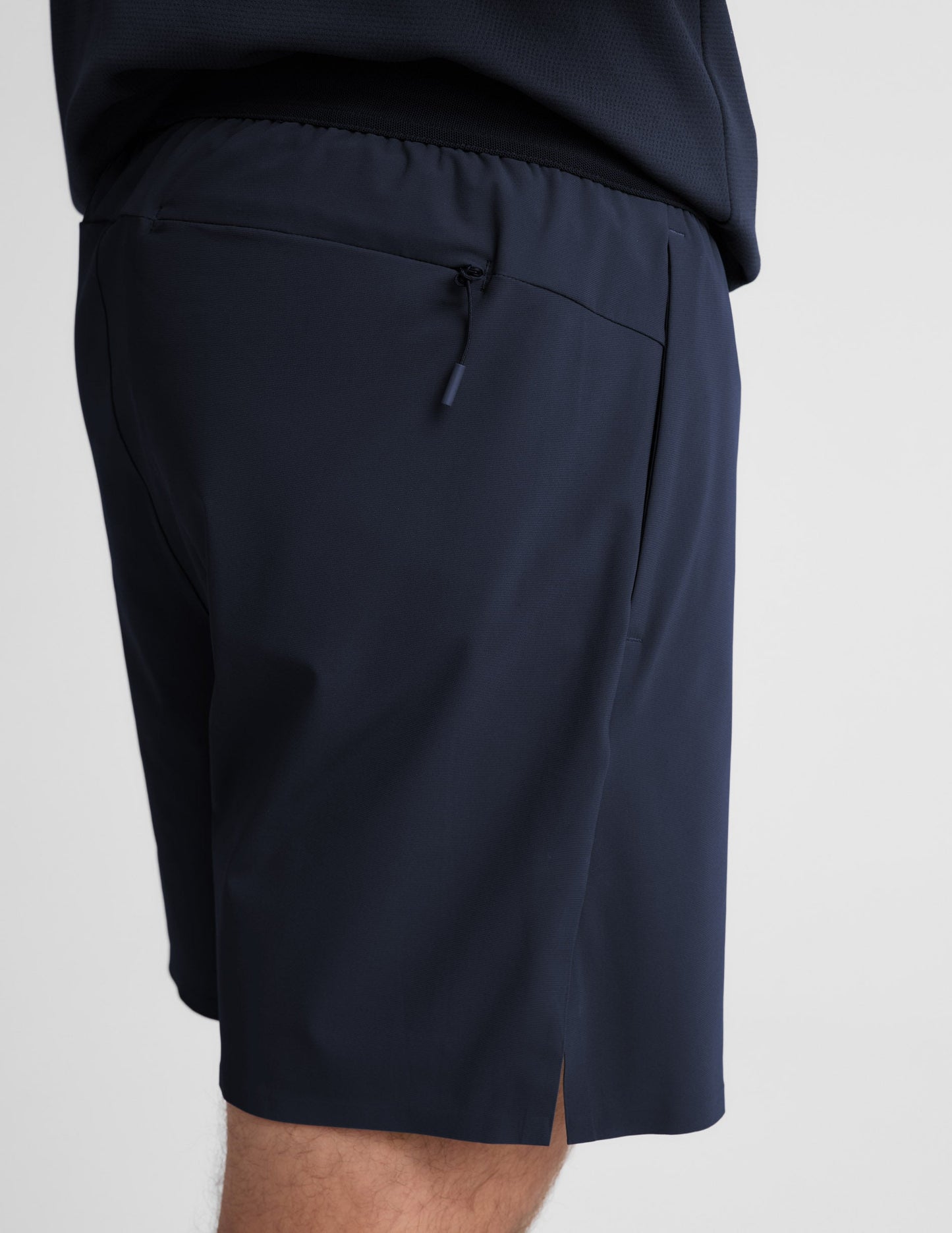 Man wearing Navy WarpLite Range Lined Short™ with a navy top, showing the rear view and zippered back pocket.