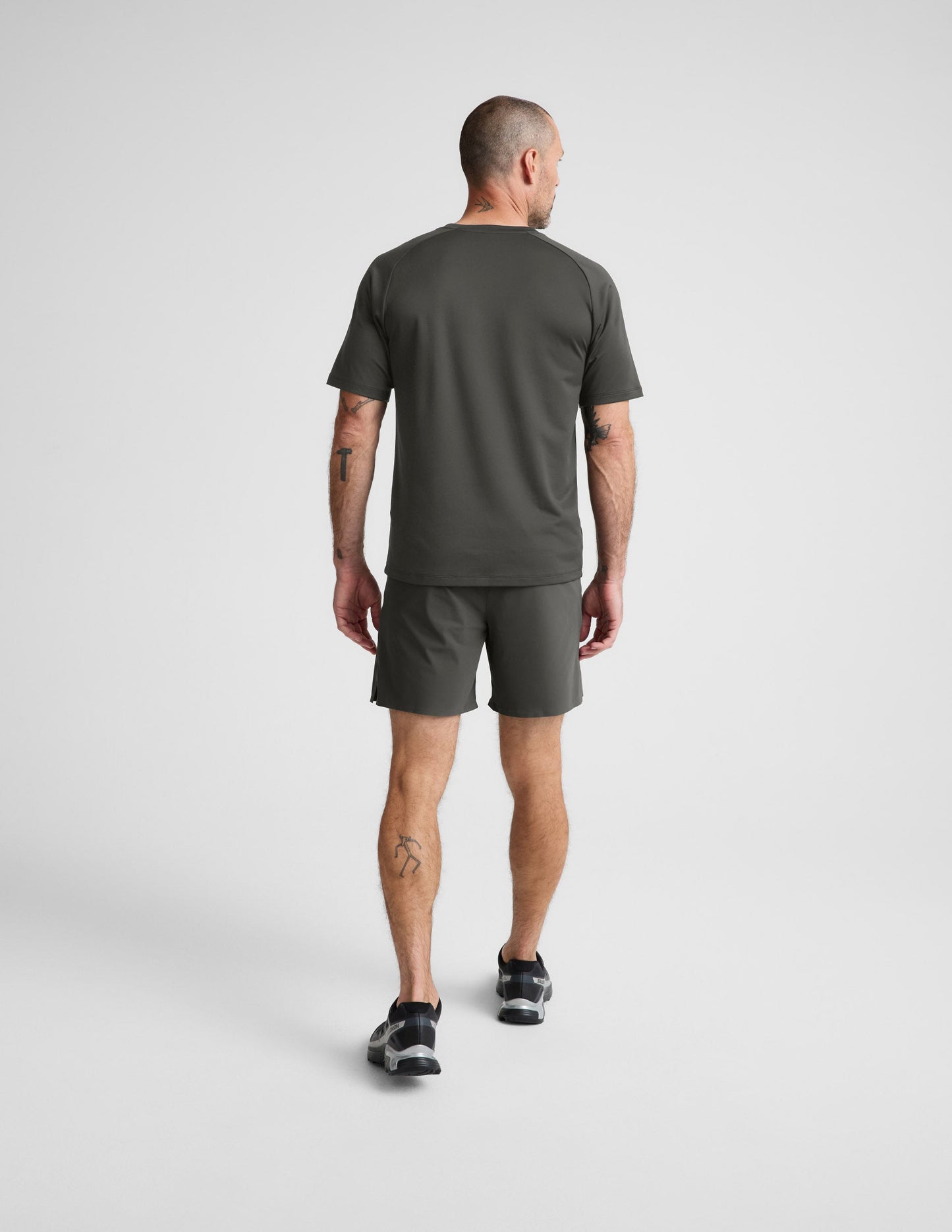 Rear view of man wearing Olive WarpLite™ Range Lined Short paired with a matching t-shirt and black sneakers.