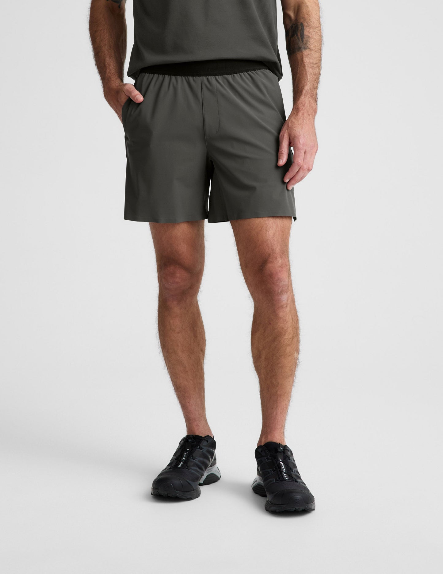 Man wearing Olive WarpLite Range Lined Short™ paired with a grey t-shirt and black sneakers.