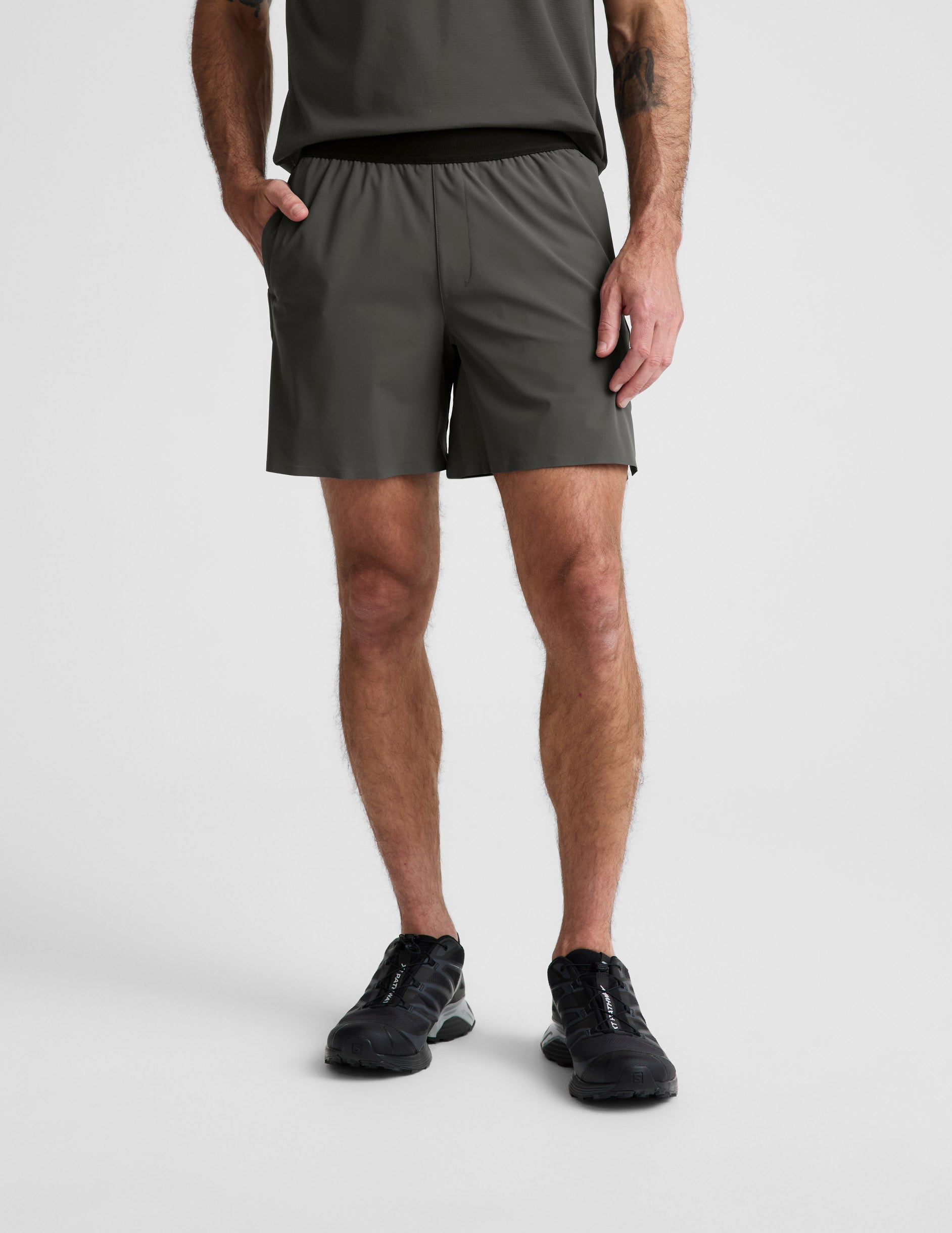 Man wearing Olive WarpLite Range Lined Short™ paired with a grey t-shirt and black sneakers.