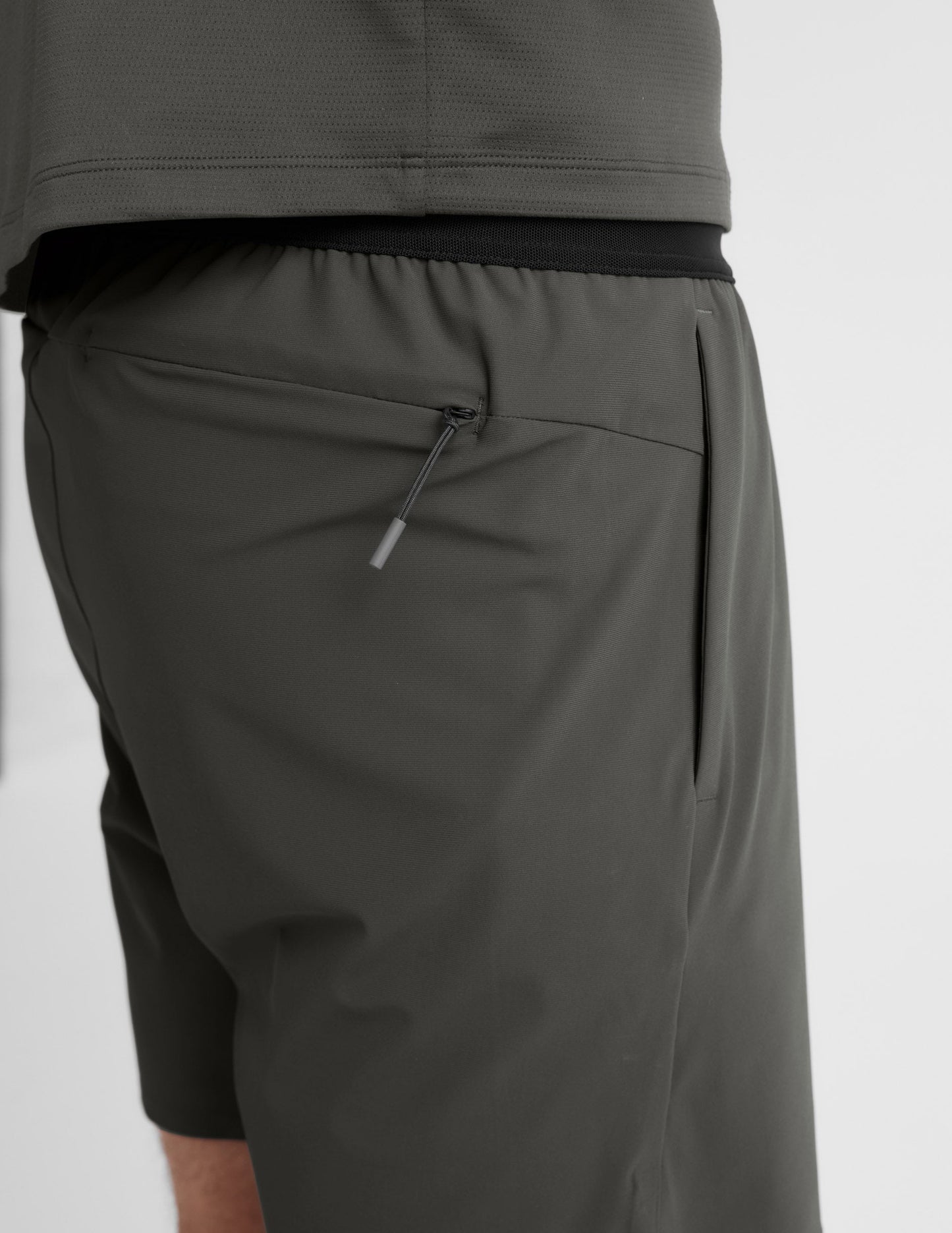 Side profile of man wearing Olive WarpLite™ Range Lined Short with zipper pocket, paired with a dark grey shirt.