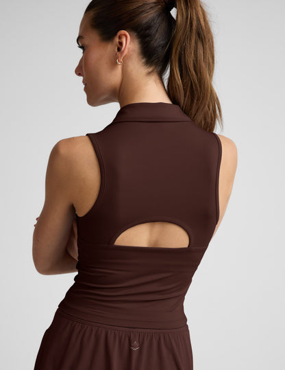 Woman wearing a brown sleeveless tank and skirt against a plain background.