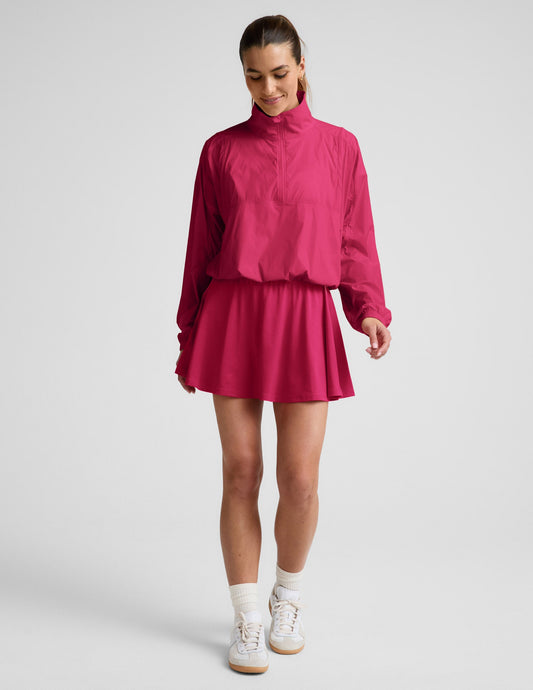 Woman wearing Fuchsia Sport Active Drawcord Mini Skirt™ with a matching half-zip pullover jacket and white sneakers.