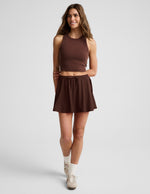 Woman wearing Brown Sport Active Drawcord Mini Skirt™ with a brown racerback tank top and white socks.