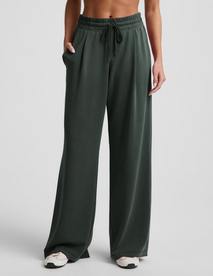 Woman wearing Dark Green Luxe Sandwash Double Knit Wide Leg Pant with front pleats, paired with cream sneakers.