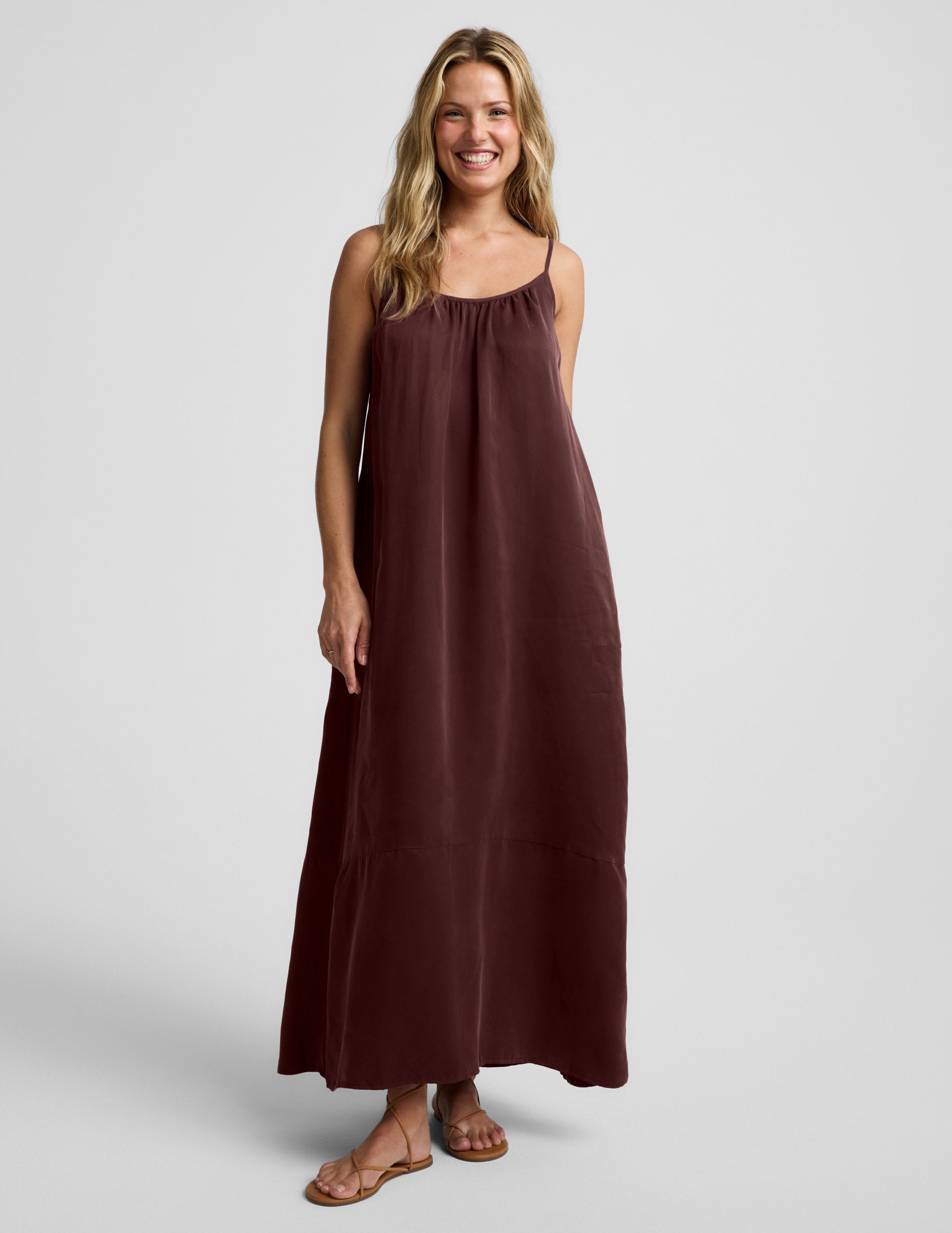 Woman wearing a brown maxi cupro dress against a plain background.
