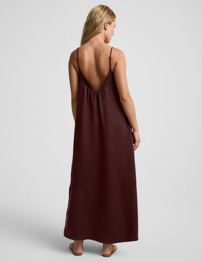 Woman wearing a brown maxi cupro dress against a plain background.