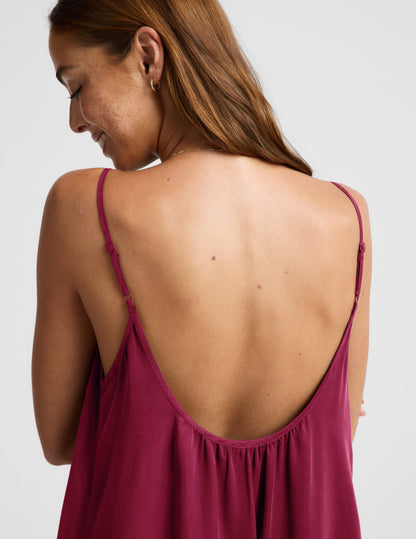 Woman wearing a red maxi cupro dress against a plain background.