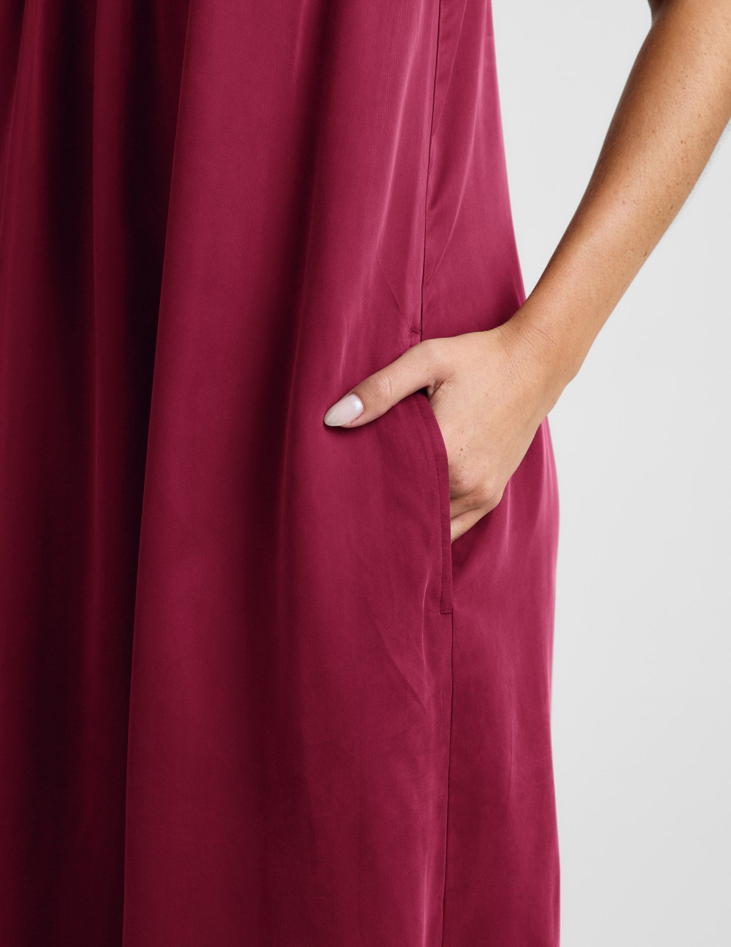 Woman wearing a red maxi cupro dress against a plain background.