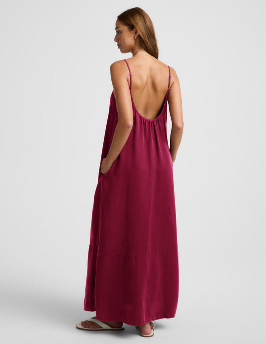 Woman wearing a red maxi cupro dress against a plain background.