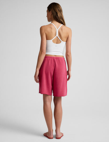Woman wearing Pink Fade Out™ Low-Rise Bermuda Short, rear view, paired with a white racerback crop top.