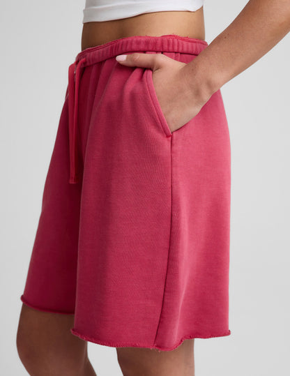 Side profile of woman wearing Pink Fade Out™ Low-Rise Bermuda Short with a raw hem, paired with a white crop top.