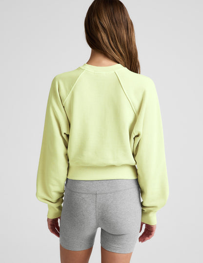 Woman wearing a yellow cropped sweatshirt and gray biker shorts against a plain background.