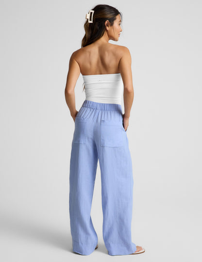 Woman wearing Blue SoftWash Linen Easy Wide Leg Pant 31" paired with a white strapless top, Rear view.
