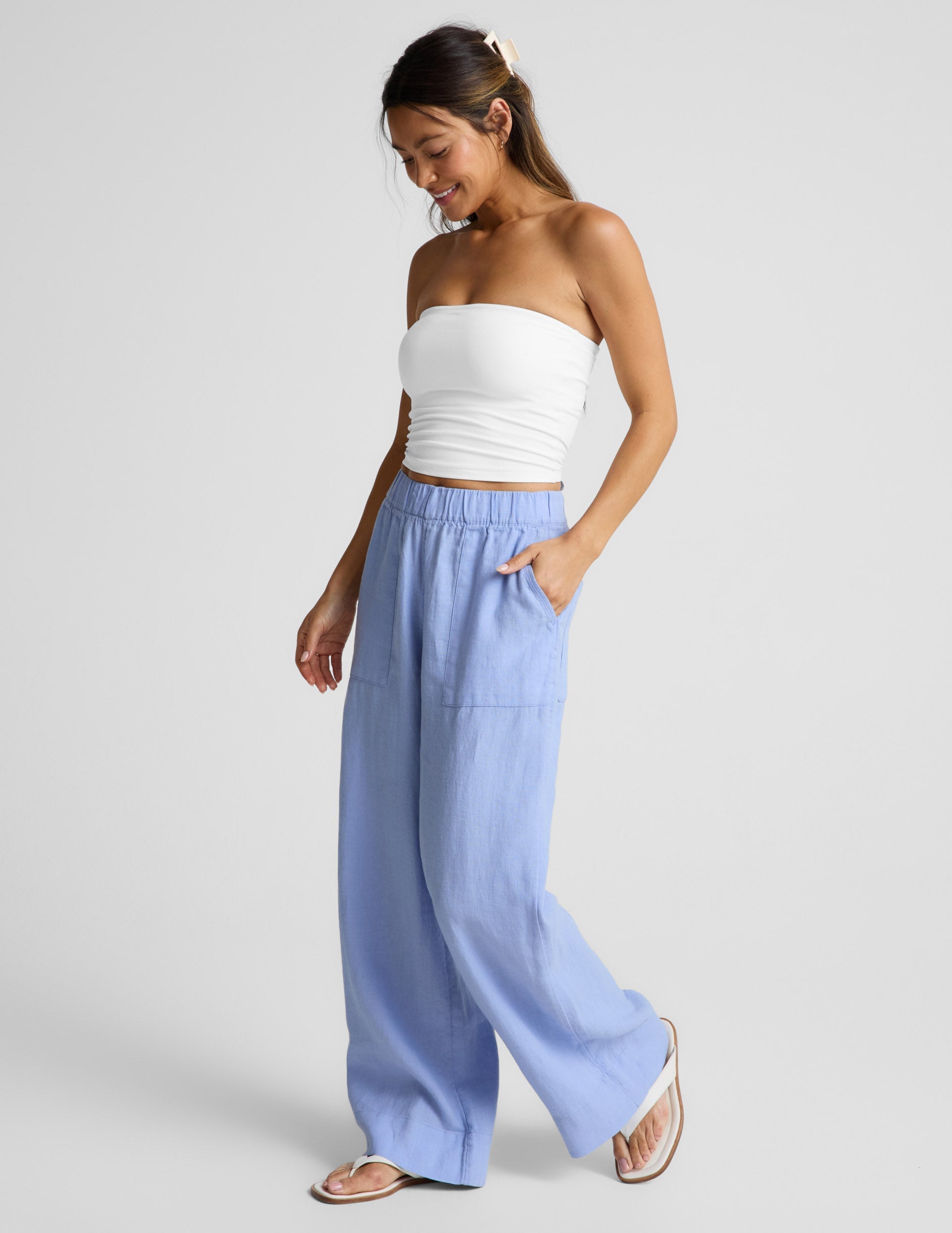 Woman wearing Blue SoftWash™ Linen Easy Wide Leg Pant 31" with a hand in pocket, paired with a white tube top.