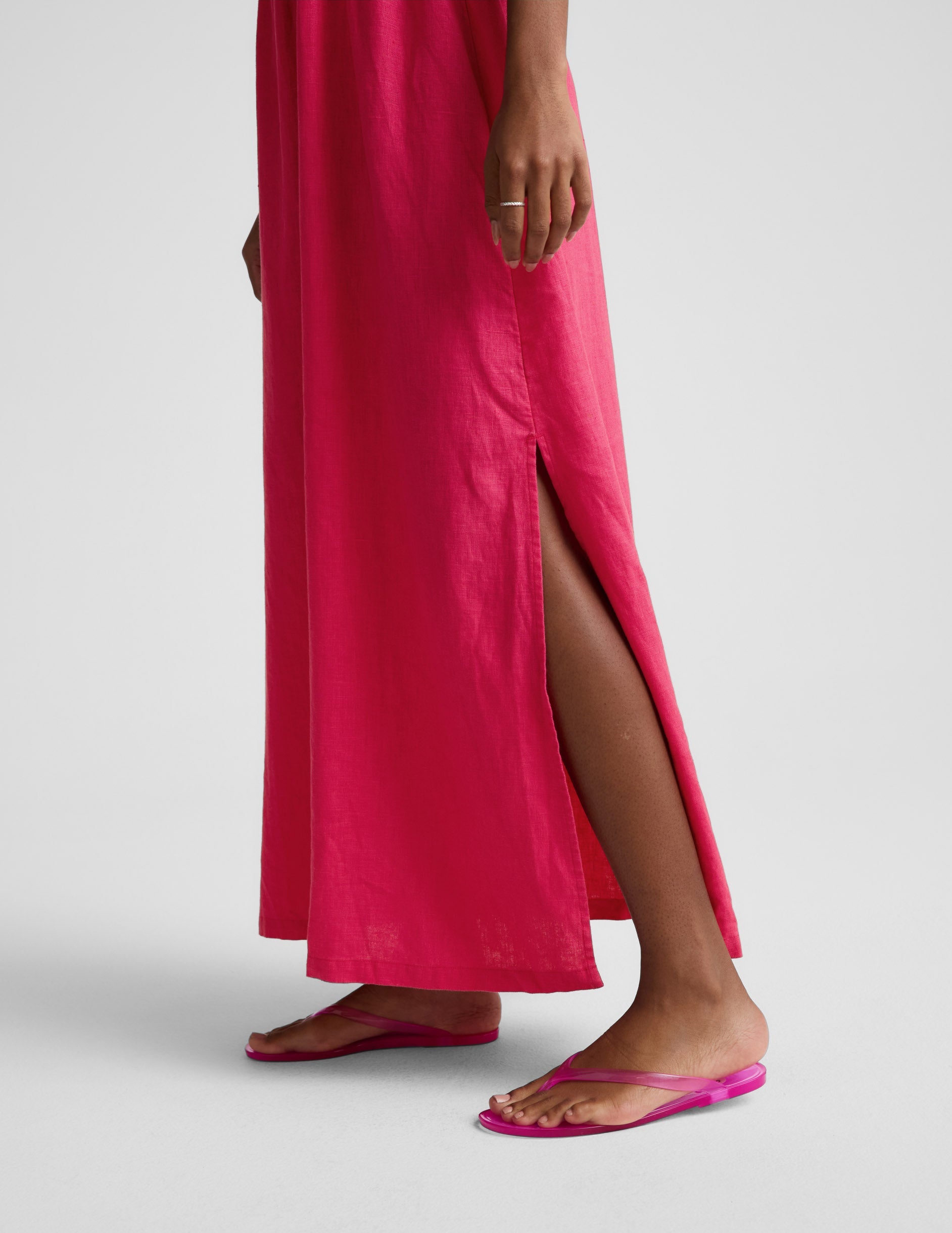 Woman wearing a red linen halter maxi dress against a plain background.
