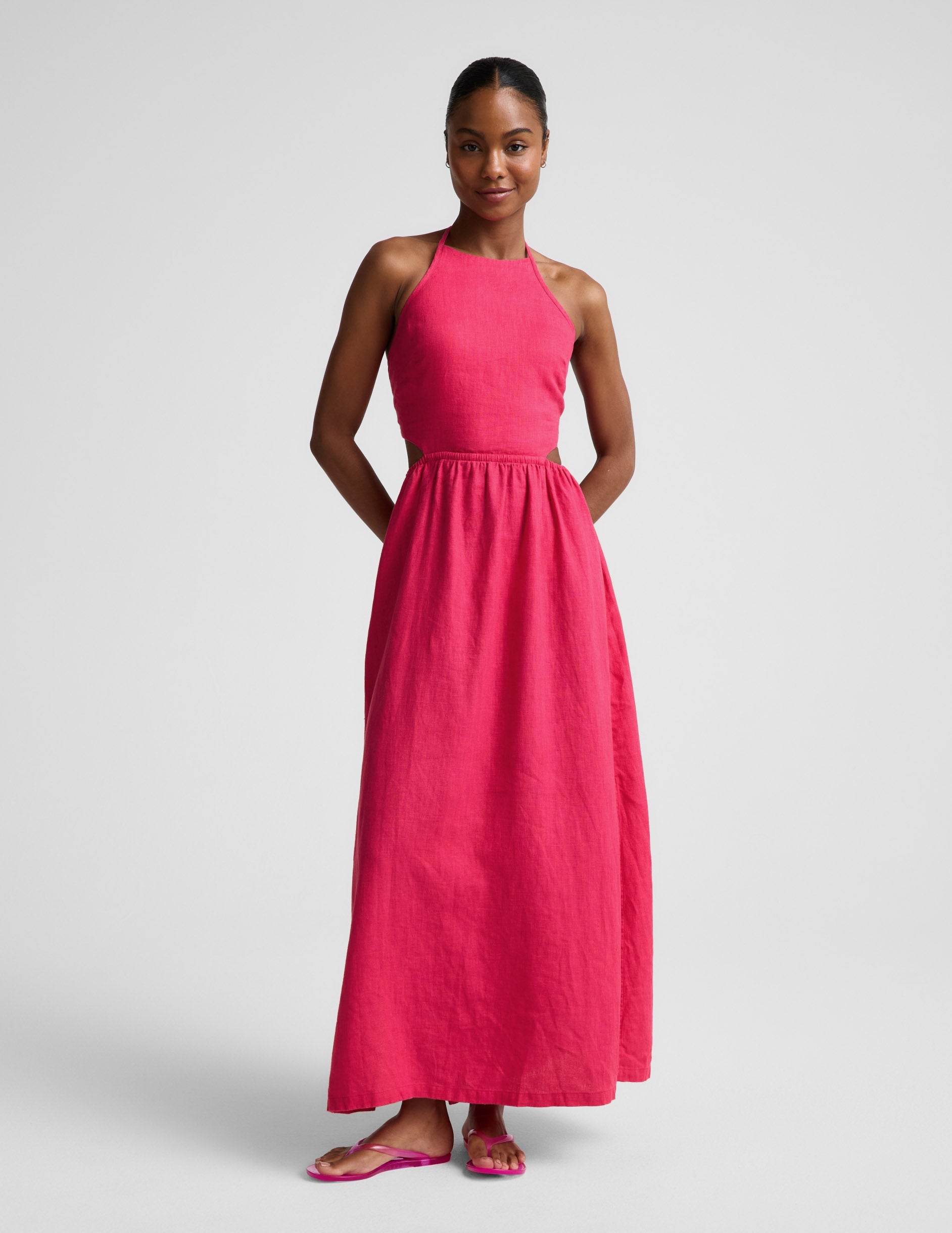 Woman wearing a red linen halter maxi dress against a plain background.