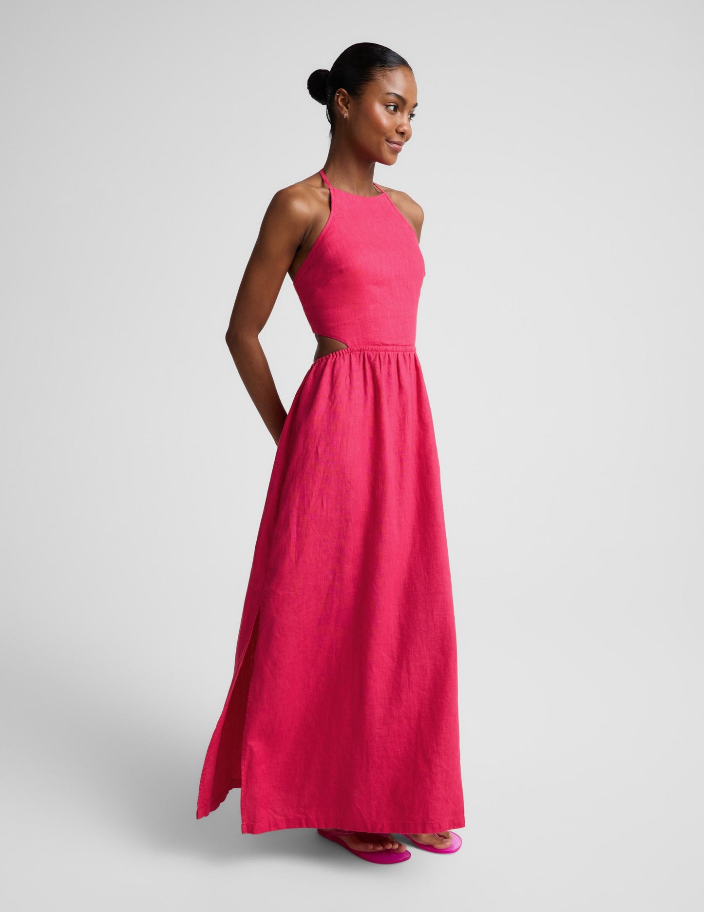 Woman wearing a red linen halter maxi dress against a plain background.