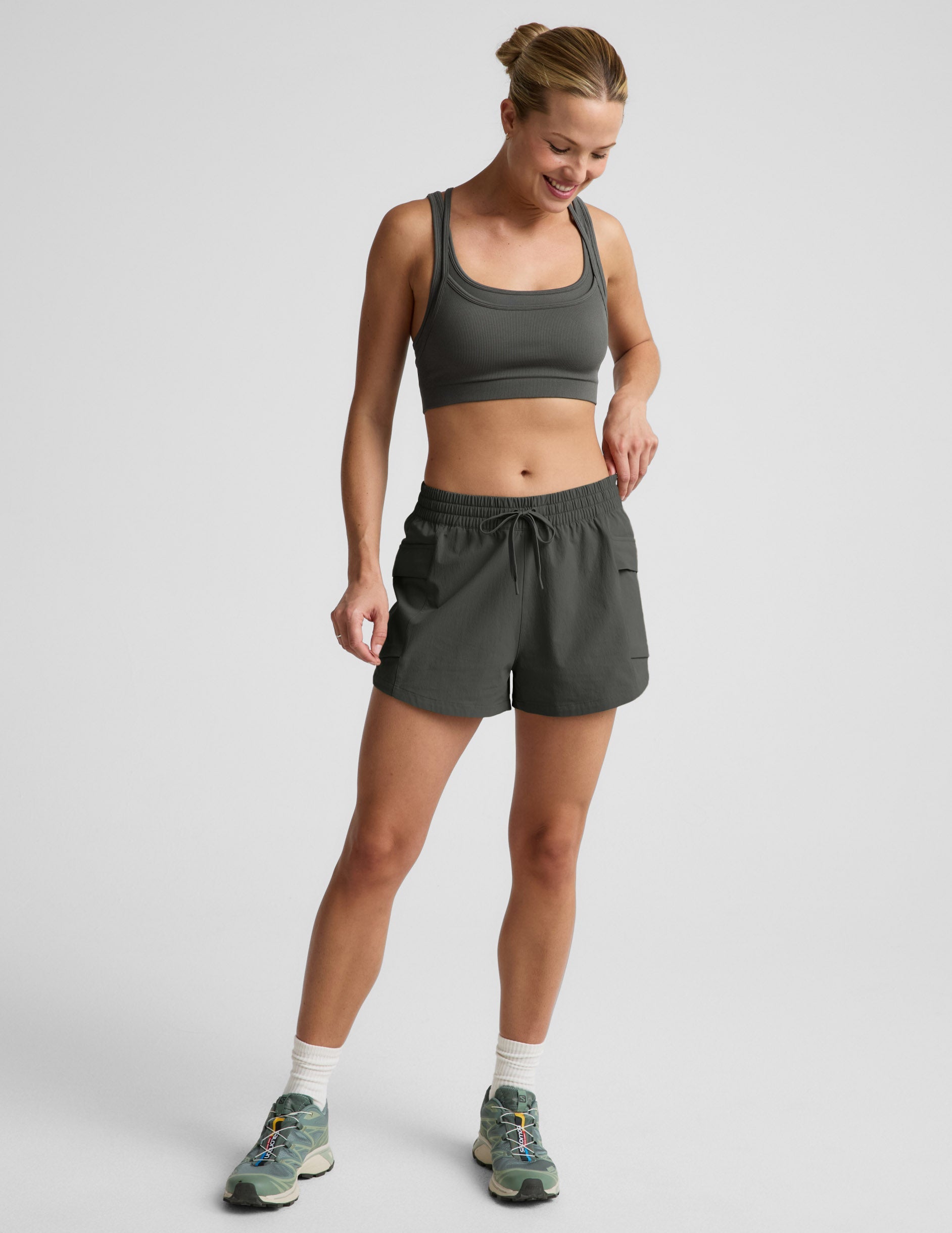 Woman wearing a green sports bra and shorts against a plain background.