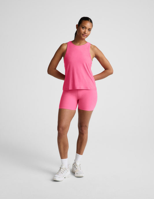Woman wearing a pink tank top and biker shorts against a plain background.