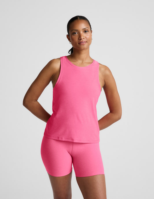 Woman wearing a pink tank top and biker shorts against a plain background.