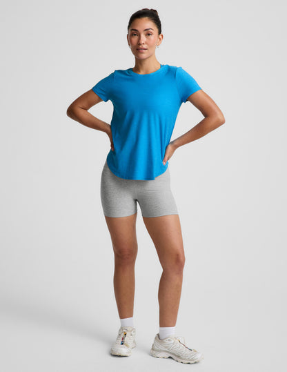 Woman wearing a blue t-shirt and gray biker shorts against a plain background.