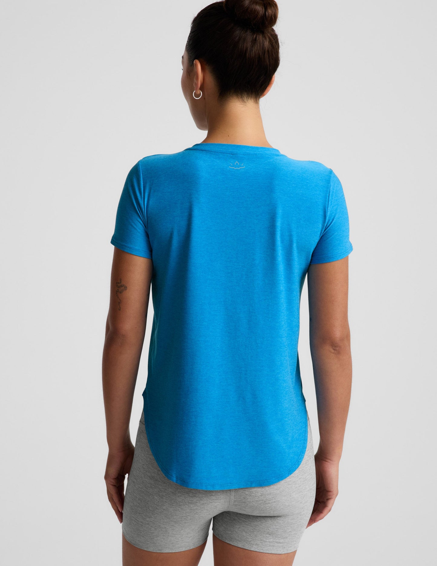 Woman wearing a blue t-shirt and gray biker shorts against a plain background.